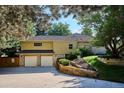 Two-car garage featuring an extended driveway with lush landscaping in the backyard at 10601 E Crestline Ave, Englewood, CO 80111