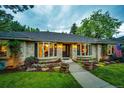 Lovely brick home featuring a well-manicured lawn, colorful flowerbeds, and a charming walkway leading to the entrance at 10601 E Crestline Ave, Englewood, CO 80111