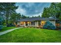 Inviting single-story brick home with lush green lawn, mature trees, and a welcoming walkway to the front entrance at 10601 E Crestline Ave, Englewood, CO 80111