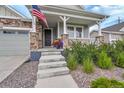 Inviting covered front porch with stone pillars, steps leading to the entry and surrounding garden beds at 8839 Culebra St, Arvada, CO 80007