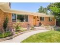 Lovely brick home with landscaped garden beds and a curved walkway leading to the front door at 3025 S Norman Ct, Denver, CO 80224