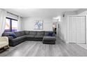 Spacious living room featuring gray wood floors, a large sectional sofa, and natural light at 3345 S Ammons St # 5-102, Lakewood, CO 80227