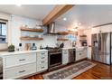 Modern kitchen with white cabinets, stainless steel appliances, open shelving, and hardwood floors at 6361 S Spotswood Cir, Littleton, CO 80120