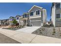Charming two-story home featuring a stylish gray exterior, landscaped yard, and an attached two-car garage at 305 Welded Tuff Trl, Castle Rock, CO 80104