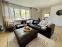 Bright living room features a comfortable leather sectional, neutral rug, and light-filled windows at 4934 S Flower Way, Littleton, CO 80123