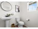 A stylish powder room features a pedestal sink, round mirror, and modern decor at 10917 Mobile St, Commerce City, CO 80022