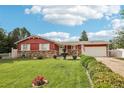 Quaint single-story home with a green lawn, vibrant flowerbeds, charming stone details, and tidy, green shrubbery at 14791 E Security Pl, Aurora, CO 80011
