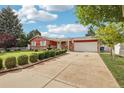 Landscaped front yard view showcasing the home's red exterior, extended driveway, and decorative shrubbery at 14791 E Security Pl, Aurora, CO 80011