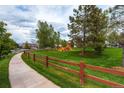 Community playground with wood fence, green space, walking path, and play equipment at 10882 Bullock Ct, Parker, CO 80134