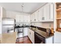 Updated kitchen showcasing stainless steel appliances, granite counters, white cabinets, and dark hardware at 1121 Albion St # 803, Denver, CO 80220