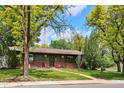 Charming single-story home with lush front yard, brick accents, and mature trees at 850 Idalia Cir, Aurora, CO 80011