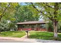 Charming single-story home with lush front yard, brick accents, and mature trees at 850 Idalia Cir, Aurora, CO 80011