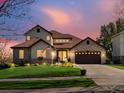 Charming two-story home with a stone-accented facade, three-car garage, and a well-manicured lawn at twilight at 6266 W Prentice Ave, Littleton, CO 80123