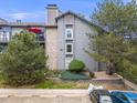 View of the condo's exterior showing stone accents, landscaping, and parking area at 2575 S Syracuse Way # K201, Denver, CO 80231