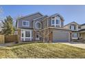 Charming two-story home with gray siding, brick accents, manicured lawn, and attached two-car garage at 13322 Marion St, Thornton, CO 80241