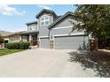 Charming two-story home with a well-manicured lawn, two-car garage and appealing gray siding with stone accents at 10730 Hillrose St, Parker, CO 80134