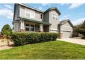 Beautiful home featuring a lush green lawn, manicured bushes, gray siding, and a welcoming front porch at 10730 Hillrose St, Parker, CO 80134