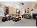 Comfortable living room features neutral walls, vaulted ceiling, ceiling fan, fireplace, and plush seating at 6267 N Dunkirk Ct, Aurora, CO 80019