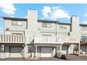 Townhouse featuring multiple balconies, garages, and a neutral color scheme under a bright blue, partially cloudy sky at 9044 W 63Rd Ave, Arvada, CO 80004