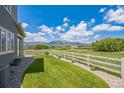 Beautiful backyard featuring a lush green lawn, white fence, and scenic mountain views at 1842 Peak Prairie Ln, Monument, CO 80132