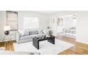 Bright living room with hardwood floors, modern furnishings, and an open layout leading to the dining area at 7060 S Windsor St, Littleton, CO 80128