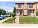 Inviting townhome with red and tan exterior, featuring a charming front entrance and well-maintained landscaping at 14465 E Hawaii Cir # A, Aurora, CO 80012
