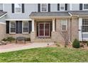 Inviting entrance with a cozy bench, meticulous landscaping, and a red screen door adding character to the brick facade at 20363 E Top T Ranch Pl, Parker, CO 80134
