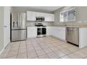 Modern kitchen with stainless steel appliances, granite countertops, white cabinets, and tile flooring at 11803 W Tufts Pl, Morrison, CO 80465
