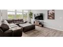 Comfortable living room with hardwood floors, brown leather sectional, and large windows at 870 Mosquito Ct, Elizabeth, CO 80107