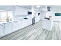Modern kitchen featuring white cabinetry, stainless steel appliances, and light wood flooring at 815 Plum Ave, Lochbuie, CO 80603