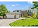 Inviting two-story home with a three-car garage, brick accents, and a green lawn at 8806 Tuscany Ln, Highlands Ranch, CO 80130