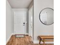 Inviting entryway with light walls, wood floors, a wooden bench, and a stylish round mirror at 2418 Coach House Loop, Castle Rock, CO 80109