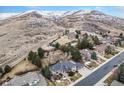 Expansive aerial view of a luxury home nestled in the foothills of a snow-capped mountain range at 15846 W Bayaud Dr, Golden, CO 80401