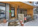 Modern home entry with wood and stone details, snowy porch at 3915 W Byron Pl, Denver, CO 80212