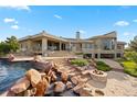 Luxurious home features an inviting patio with a stone fire pit and waterfall spilling into the dazzling pool at 606 Cliffgate Ln, Castle Rock, CO 80108