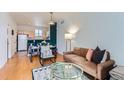 Inviting living room with hardwood floors, stylish furnishings, and a view of the adjacent dining area and kitchen at 85 Uinta Way # 702, Denver, CO 80230