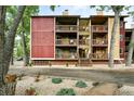 Multi-story condo building with red and yellow siding, featuring private balconies and landscaped grounds at 2960 Shadow Creek Dr # 201, Boulder, CO 80303