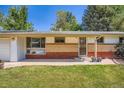 Close-up of the front of a single-story house with brick and a well-kept yard at 8075 Sunset Dr, Lakewood, CO 80214