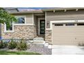 Close up of the home's entrance, with a modern door, stone accents, and well-kept landscaping at 722 Eva Peak Dr, Erie, CO 80516