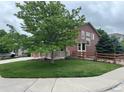 Two-story home with mature trees, manicured lawn, and a cozy front porch at 10614 Kicking Horse Dr, Littleton, CO 80125