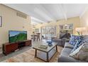 Bright living room featuring beamed ceilings, neutral paint, and hardwood floors with grey sofa and access to deck at 130 N Pearl St # 304, Denver, CO 80203
