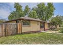 Well-maintained home featuring a brick exterior, a wooden fence, and lush green lawn, providing a cozy and private setting at 5600 Dover St, Arvada, CO 80002