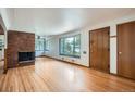 Bright living room with hardwood floors, a brick fireplace, and large windows offering plenty of natural light at 5600 Dover St, Arvada, CO 80002