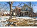 Neighborhood view showing colorful home with a front porch surrounded by a tree and snow on the lawn at 2336 N High St, Denver, CO 80205