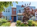 Modern townhouse showcasing blue siding, brick detail, and a small balcony, enhanced by decorative trees and green shrubs at 2346 Central Park Blvd, Denver, CO 80238