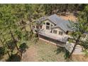 Aerial view of a charming home featuring an expansive deck, mature trees, and a sprawling yard at 510 Hill Dr, Sedalia, CO 80135