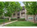 Multi-story condo building with lush landscaping and a well-maintained green lawn at 9160 E Arbor Cir # F, Englewood, CO 80111