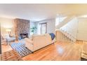 Bright living room with hardwood floors, stone fireplace, and staircase at 6420 E Bates Ave, Denver, CO 80222