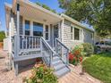 Inviting covered front porch with seating, fresh landscaping, and brick walkway to the home's entrance at 3645 S Fox St, Englewood, CO 80110