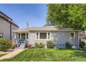Single-story home featuring manicured lawn, mature trees, and a quaint front porch with bench seating at 3645 S Fox St, Englewood, CO 80110